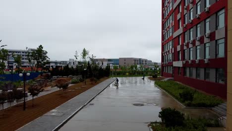 Zwei-Chinesische-Arbeiter,-Die-Nach-Dem-Regen-Den-Bürgersteig-Fegen---Weihai-Campus-Der-Jiaotong-universität-Beijing,-China