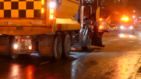 Snow-plowing-truck-with-flashing-lights-backing-up-in-night-time