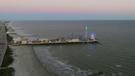 Luftaufnahme,-Die-Sich-Dem-Historischen-Vergnügungspier-Der-Insel-Galveston-Nähert,-Bunter-Abend-In-Texas,-Usa