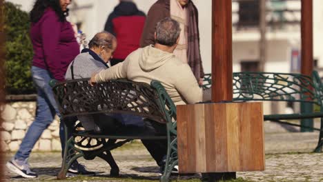 Gente-Local-Sentada-En-Un-Banco-En-La-Calle-Nazare,-Portugal,-Hablando-Juntos