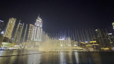 Weite-Ansicht-Mit-Der-Wassershow-Vom-Dubai-brunnen-Nachts-Gesehen-Mit-Dem-Stadtbild-Als-Hintergrund
