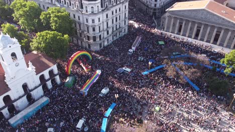 Aerial-orbit-shot-of-LGBT-Pride-Parade-in-Buenos-Aires-in-Plaza-de-Mayo-with-colorful-flags-at-sunlight