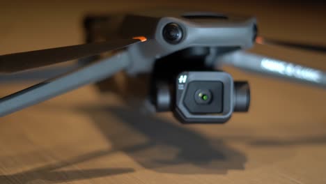 Dron-Clásico-Dji-Mavic-3-Parado-En-Un-Piso-De-Madera:-Primer-Plano-De-La-Toma-Del-Producto-De-Seguimiento-Con-Un-Enfoque-De-Bastidor-De-Poca-Profundidad-Desde-La-Hélice-Hasta-La-Cámara-Hasselblad