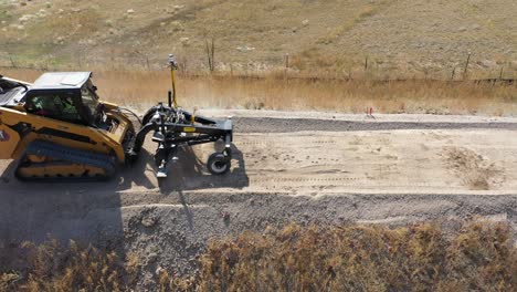 Drone-view-of-Caterpillar-compact-track-loader-levelling-gravel-road-surface