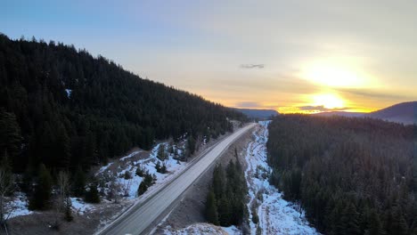 An-Aerial-shot-of-Cars-driving-on-Cariboo-Highway-97-During-a-Winter-Sunrise-in-British-Columbia,-Canada