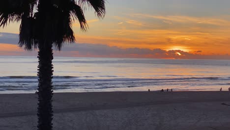 Silhouette-Kokospalmen-Mit-Einigen-Leuten,-Die-Bei-Sonnenuntergang-Am-Strand-Spazieren-Gehen