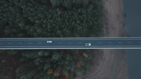 Top-Down-Aerial-View,-White-Car-Moving-on-Bridge-Above-Countryside-Forest-and-River