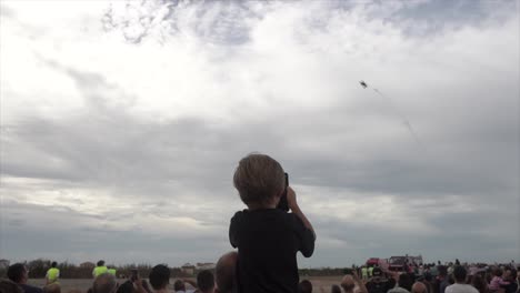 Multitud-De-Espectadores-Espectáculo-De-Aviones,-Un-Niño-En-El-Hombro-De-Su-Padre-Grabando-Acrobacias-En-Un-Smartphone,-Cámara-Lenta