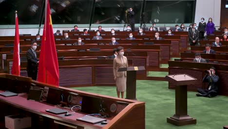 Carrie-Lam,-Ehemalige-Geschäftsführerin-Von-Hongkong,-Leitet-Die-Eideszeremonie,-Während-Sie-Neben-Den-Flaggen-Der-Volksrepublik-China-Und-Hongkongs-In-Der-Hauptkammer-Des-Legislativrates-Steht