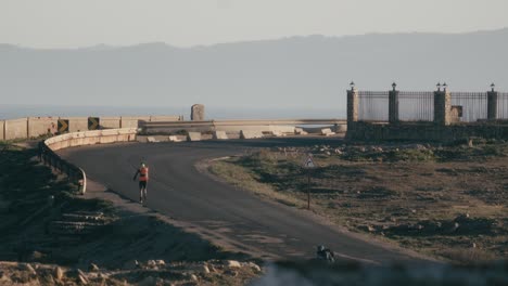 Runner-running-empty-road,-long-telephoto-lens-back-static-view