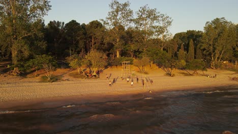 Luftaufnahme-Einer-Gruppe-Von-Freunden,-Die-Während-Des-Goldenen-Sonnenuntergangs-An-Der-Fray-Bentos-küste-In-Uruguay-Beachvolleyball-Spielen
