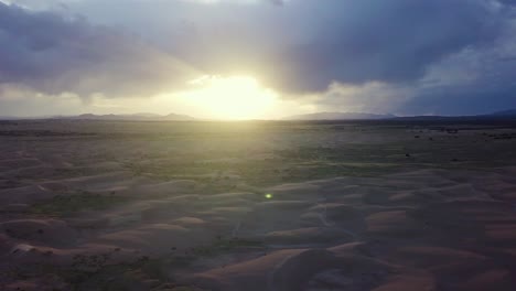Slow-aerial-descent-towards-hot,-sandy-surface-of-Mojave-Desert,-Utah,-sunset