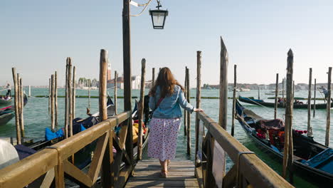 Rückansicht-Einer-Frau,-Die-Auf-Einem-Holzsteg-über-Dem-Canal-Grande-In-Venedig,-Italien,-Spazieren-Geht