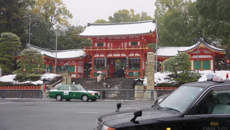 Invierno-En-Kyoto-Japón,-Los-Autos-Pasan-Por-Gion-Y-Yasaka-Jinja-En-Un-Día-Nevado