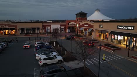 Toma-Aérea-De-Autos-Y-Personas-En-La-Plaza-Comercial-Al-Atardecer