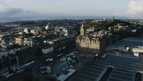 Aerial-view-pulling-away-from-Edinburgh-during-sunset-with-the-train-station-in-the-foreground
