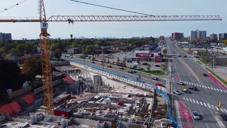 Construction-crane-building-housing-complex-at-busy-city-intersection-with-residential-and-commercial-developments