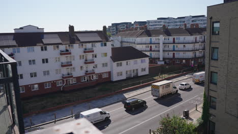 Balcony-view-overlooking-traffic-moving-through-modern-British-apartment-neighbourhood,-dolly-back-shot