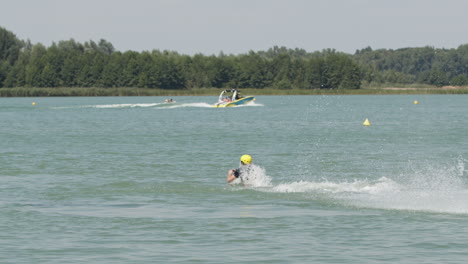 Slow-motion-shot-of-male-flyboarder-jumping-out-of-water-and-diving-into-sea-during-jet-ski-produced-water-jet