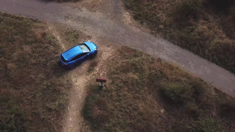 Vista-Superior-Aérea-Sobre-Un-Puma-Ford-Azul-Estacionado-Junto-A-Un-Cruce-De-Caminos-Del-País