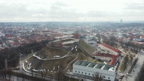 AERIAL:-Rotating-Shot-of-Vilnius-Gediminas-Tower-and-Old-Town-with-Cloudy-Sky