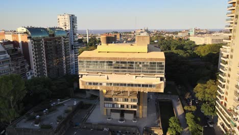 Levantamiento-Aéreo-Sobre-La-Biblioteca-Nacional-De-Estilo-Brutalista-Entre-Edificios-Y-árboles-A-La-Hora-Dorada,-Buenos-Aires