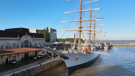 Aerial-of-parked-ARA-Libertad-frigate-being-cleaned-in-Puerto-Madero-pier-at-daytime,-Buenos-Aires