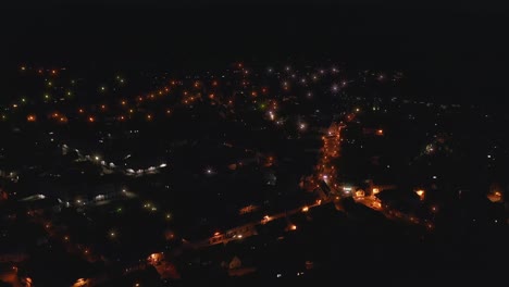 Aerial-view-over-twinkling-lights-of-a-city-at-night-with-driving-cars