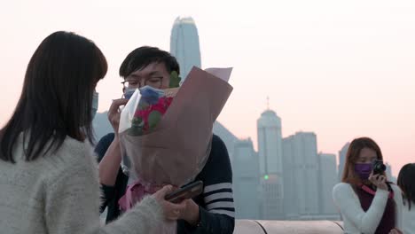 A-couple-takes-photos-along-the-Victoria-Harbour-waterfront-to-enjoy-the-view-of-the-Hong-Kong-Island-skyline-while-the-sunset-sets-in