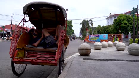 Sleeping-idle-pedicab-driver-during-Covid-pandemic,-Yogyakarta,-Indonesia