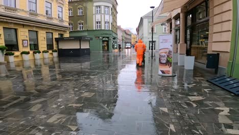 Straßenkehrmaschine-Zu-Fuß-Durch-Eine-Verregnete-Fußgängerzone-Im-Zentrum-Von-Celje,-Slowenien