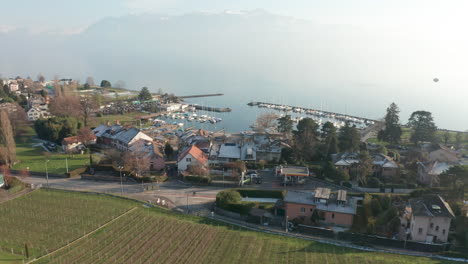 Drone-flying-over-small-Swiss-town-towards-yacht-harbor-on-lake-Geneva