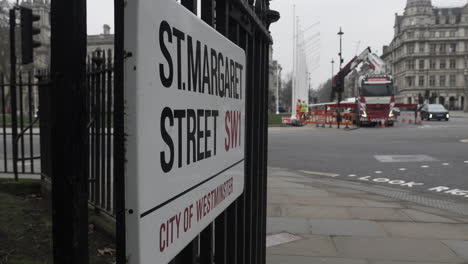 Saint-Margaret-Street-Road-Sign-On-Railings-With-Traffic-Going-Past-In-Background