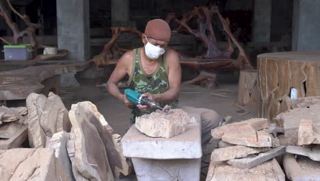 Carpenter-grinds-wood-piece-with-grinder,-dust-harm-his-not-protected-eyes