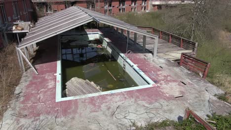 Aerial-Drone-Footage-Orbiting-to-the-Right-Around-an-Abandoned-Covered-Pool-and-Hotel