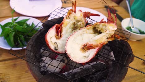 Cook-putting-fresh-lobster-halves-on-small-charcoal-grill-close-up