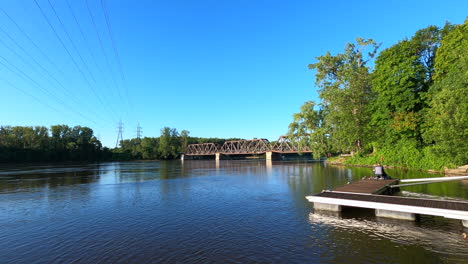 Vista-Al-Lago,-Río,-Parque,-Puente,-Cielo-Azul,-Naturaleza,-Paisaje,-Cables-Eléctricos,-Chico-Pescando