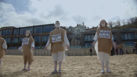 Varios-Manifestantes-Permanecen-Inmóviles-En-Una-Playa-Frente-Al-Hotel-Carbis-Bay-En-St-Ives,-Cornualles,-Reino-Unido.