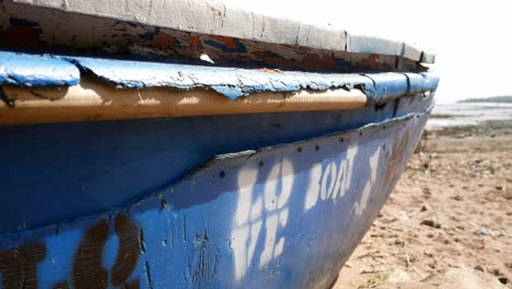 Spray-painted-love-boat-graffiti-abandoned-beached-wooden-ship-on-sandy-coastline-waterfront
