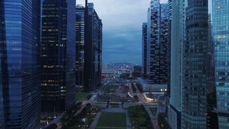 Flying-past-glass-skyscrapers-over-waterfront-boulevard-at-Marina-Bay,-Singapore