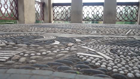 Intricate-luxury-pebble-stone-mosaic-flooring-sophisticated-balcony-tall-archway-windows-paradise-gallery-closeup-right-dolly