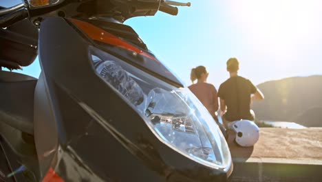 Close-up-view-of-modern-scooter-bike-and-romantic-couple-enjoying-scenery