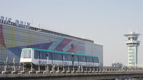 Orlyval-modern-metro-shuttle-driving-past-Paris-Orly-airport-and-control-tower