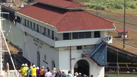 Traffic-control-tower-at-the-Miraflores-Locks,-Panama-Canal-and-people-on-the-bow-of-a-cruise-ship