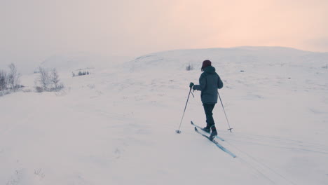 Female-cross-country-skier-exercising-alone-on-a-snowy-ski-trail-on-a-mountain-in-the-northern-Sweden