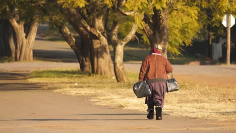 ältere-Afrikanische-Schwarze-Frau,-Die-Mit-Schweren-Taschen-Nach-Hause-Geht