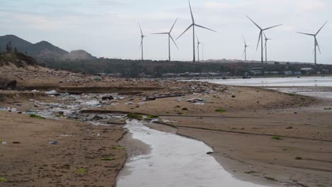 Playa-Contaminada-Con-Parque-Eólico-Visto-En-El-Fondo-En-Son-Hai,-Vietnam