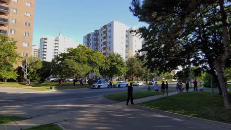 Many-police-cars-at-crime-scene-in-living-apartment-district,-people-watching