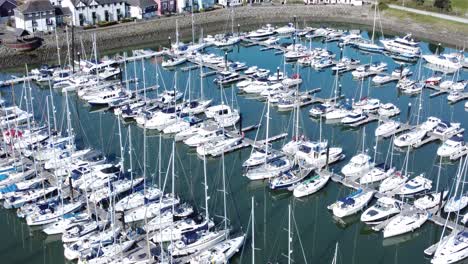 Flying-above-luxury-yachts-and-sailboats-reflections-on-sunny-Conwy-marina-birdseye-aerial-view-forward-tilt-down