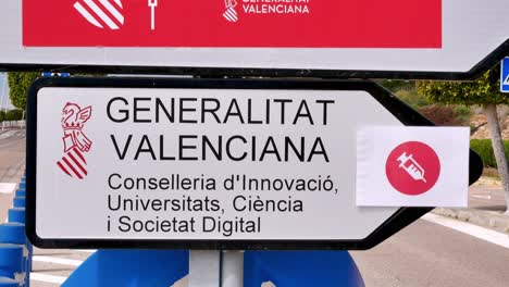 Inclinarse-Hacia-Abajo-Sobre-Un-Par-De-Señales-De-Tráfico-Que-Apuntan-A-Un-Centro-De-Vacunación